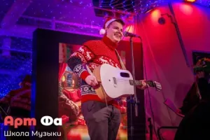 Широкая искренняя улыбка прямо у микрофона, рука соскочила со струн – Новогодний концерт, декабрь 2023